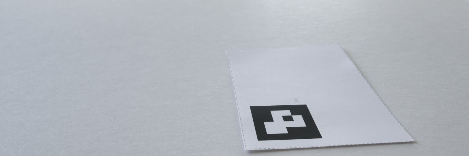 Raking light across the paper field: one card lying on it, its perforated edge and printed marker catching the light.