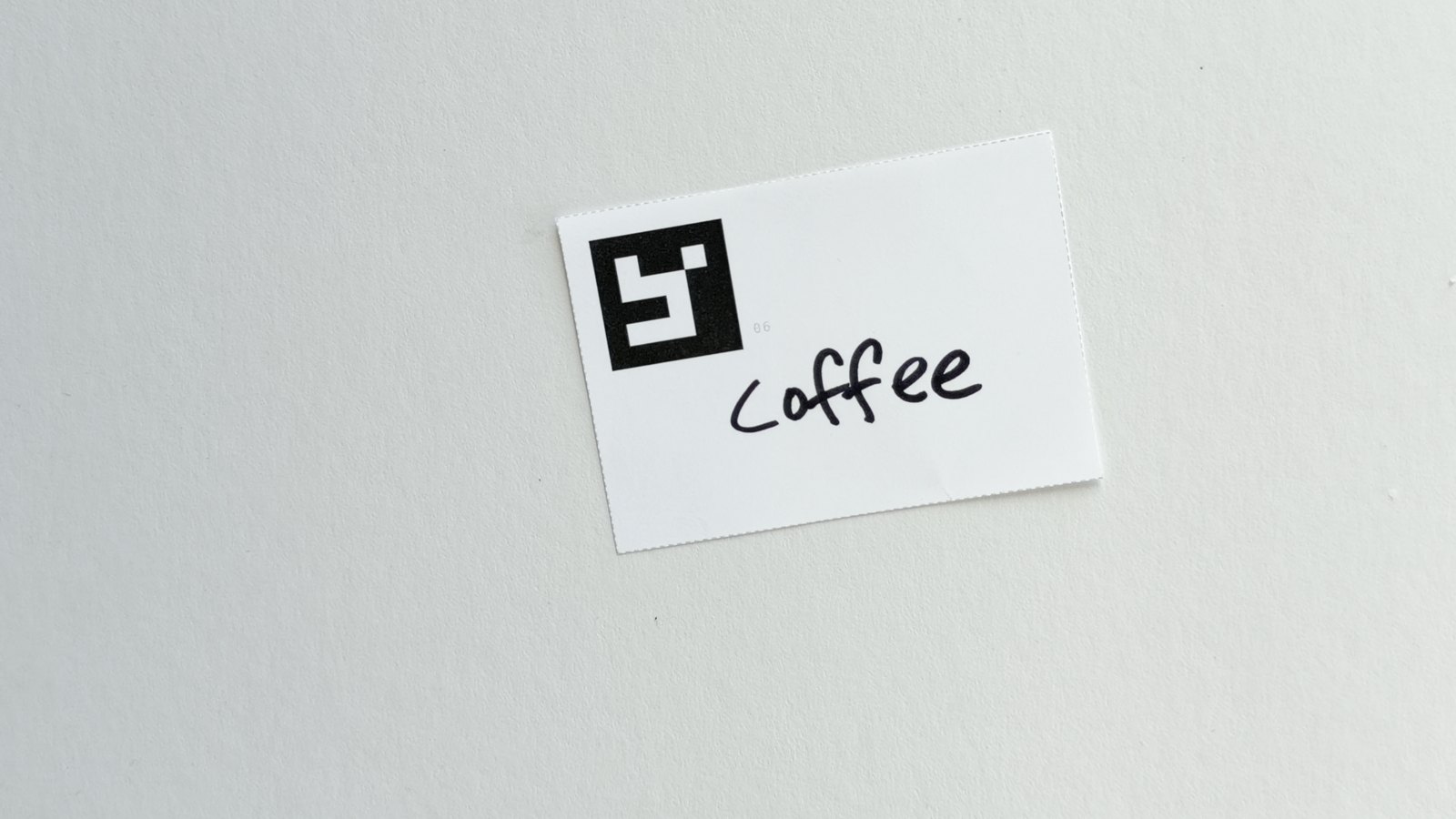 A hand writing a word on a card; the card&rsquo;s marker and the written word are in the same frame.